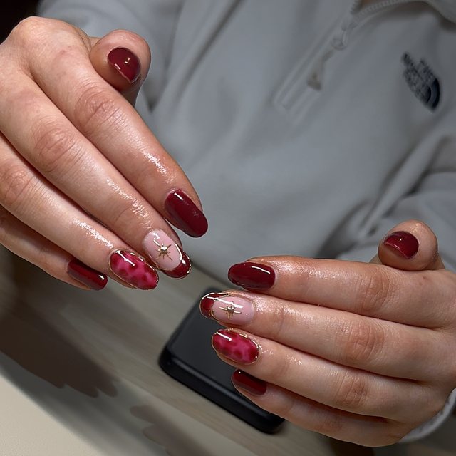 Deep red nails with pink leopard print and gold star accents